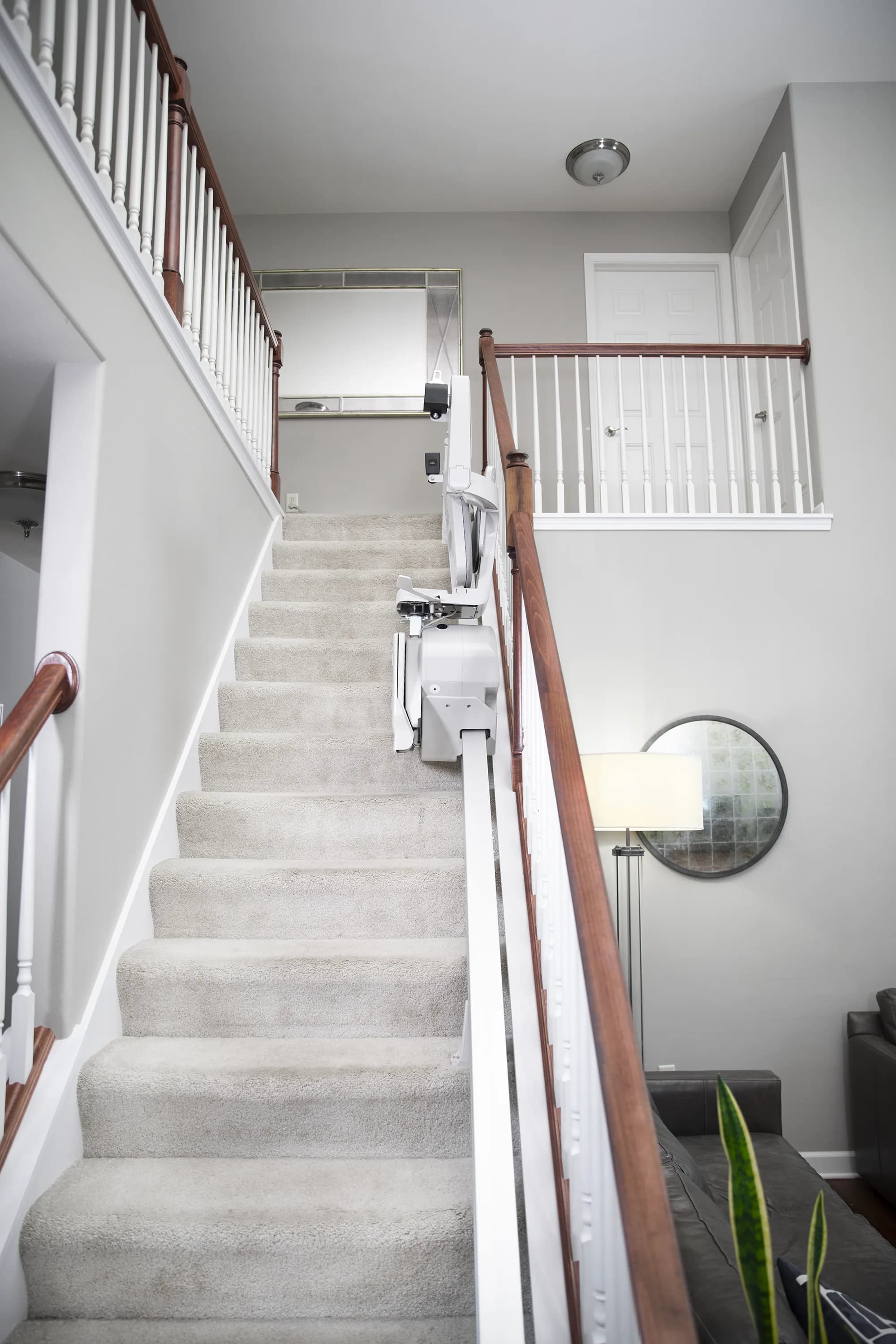 Bruno Elan SRE-5000 stairlift folded compactly on a straight indoor staircase, showing the narrow rail profile against the wall